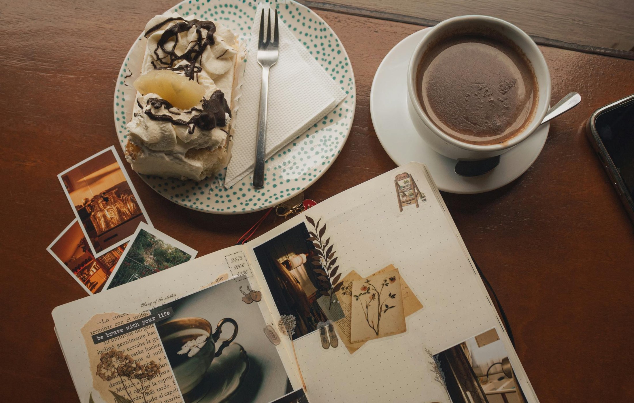 Café, un pastel y un cuaderno abierto sobre una mesa de madera
